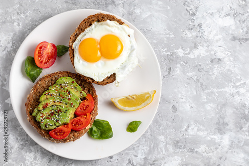 Avicado toast. Egg sandwich appetizer. Top view of balanced brunch food with rye bread. Healthy vegetarian dish recipe with tomato, basil and chili. Gourmet snack. Fitness vegan burger. Copy space photo