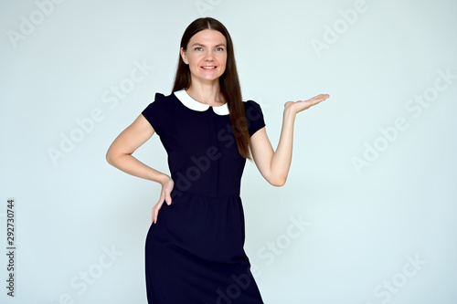 Portrait of a pretty young brunette woman with combed hair on a white background in a dark blue dress. It is in different poses. Looks straight at the camera. Slim figure.