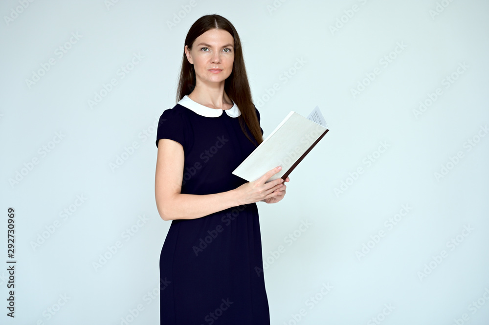 Portrait of a pretty young brunette woman with combed hair on a white background in a dark dress. He stands in different poses with a folder in his hands. Looks straight at the camera. Slim figure. Portrait of a pretty young brunette woman with combed hair on a white background in a dark dress. He stands in different poses with a folder in his hands. Looks straight at the camera. Slim figure.