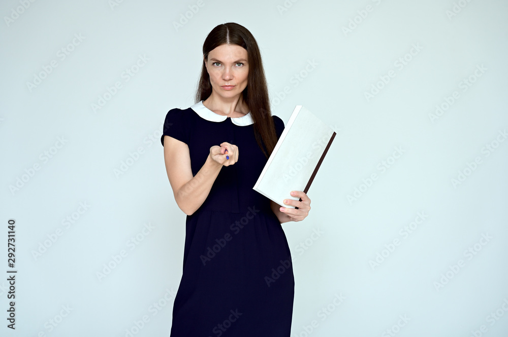 Portrait of a pretty young brunette woman with combed hair on a white background in a dark dress. He stands in different poses with a folder in his hands. Looks straight at the camera. Slim figure. Portrait of a pretty young brunette woman with combed hair on a white background in a dark dress. He stands in different poses with a folder in his hands. Looks straight at the camera. Slim figure.