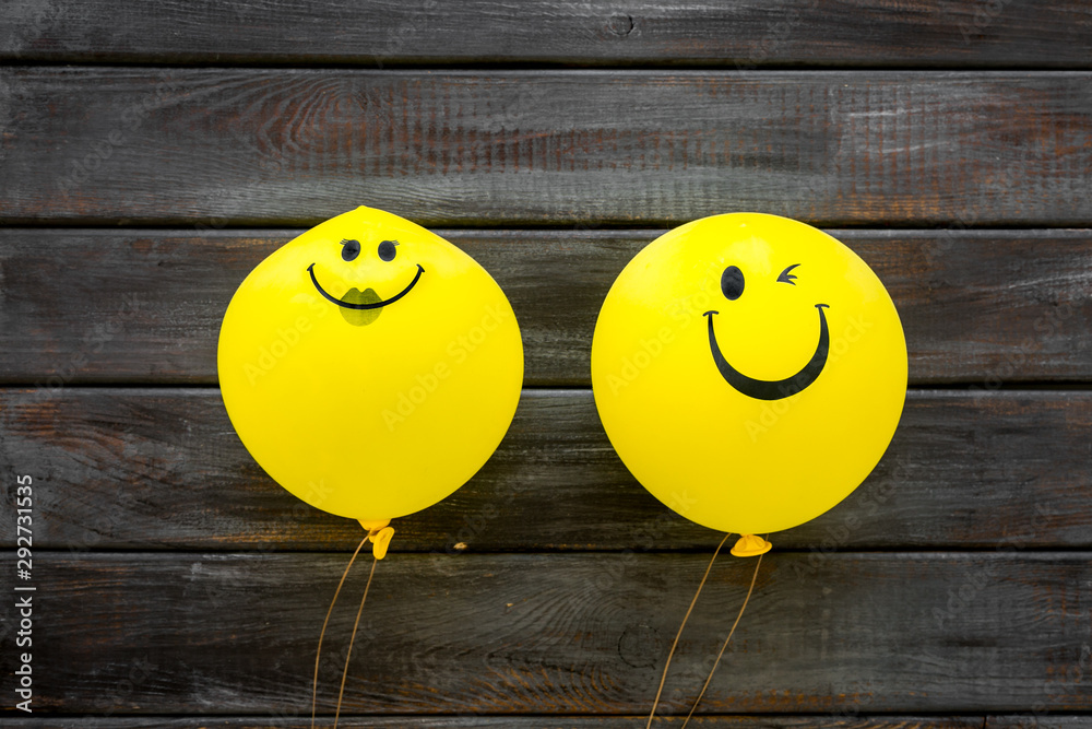 Naklejka Happiness emotion. Yellow balloon with smile on dark wooden background top view