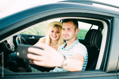 Young couple taking a selfie in car. Road trip