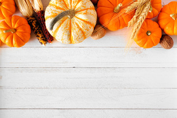Autumn top border of pumpkins and fall decor on a rustic white wood background with copy space