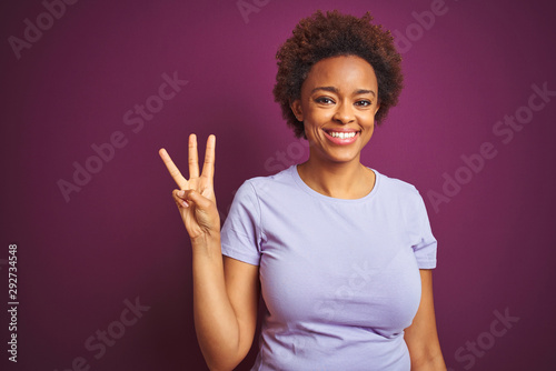 Young beautiful african american woman with afro hair over isolated purple background showing and pointing up with fingers number three while smiling confident and happy.
