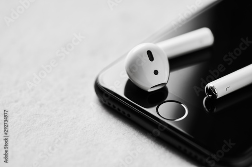 Φωτογραφία White wireless bluetooth earphones or headphones on smartphone over concrete background
