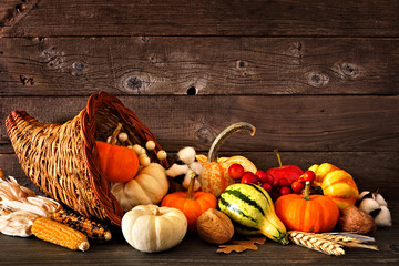 Thanksgiving cornucopia filled with autumn pumpkins and vegetables against a rustic dark wood background