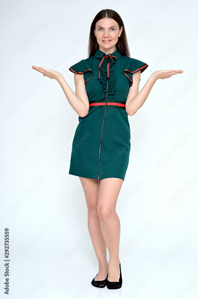 Vertical Full-length portrait of a pretty young brunette woman with combed hair on a white background in a green dress. It is in different poses. Looks straight at the camera. Slim figure.
