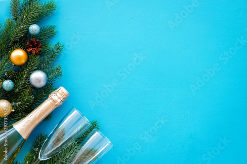 New Year decoration with champagne bottle and fir branches on blue background top view frame copy space