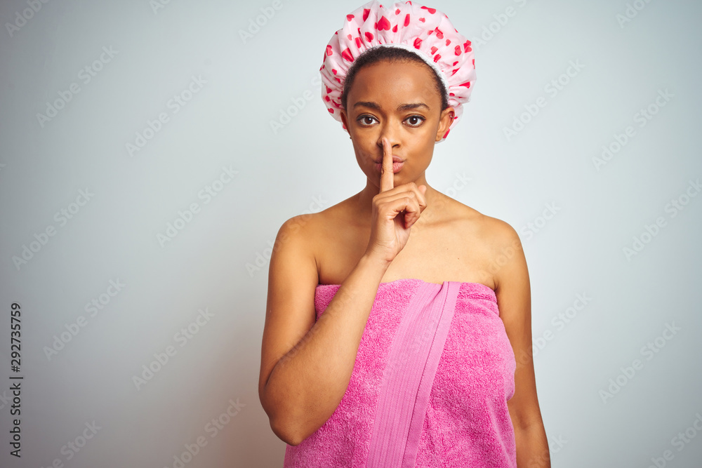 African american woman wearing pink shower towel after bath over isolated background asking to be quiet with finger on lips. Silence and secret concept. African american woman wearing pink shower towel after bath over isolated background asking to be quiet with finger on lips. Silence and secret concept.