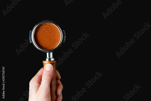man holds portafilter with ground coffee on a dark gray background photo