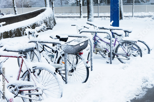 many bicycles under the snow, littered, snowfall in the city