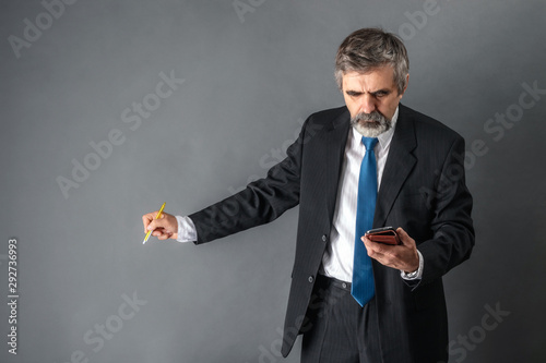 Professor gives a lecture with a smartphone in his hand, explains the teaching material, pointing with a pen