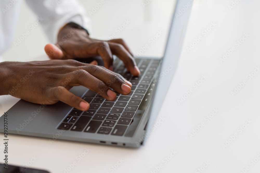 Close up of african business man hands working using keyboard of computer laptop Close up of african business man hands working using keyboard of computer laptop