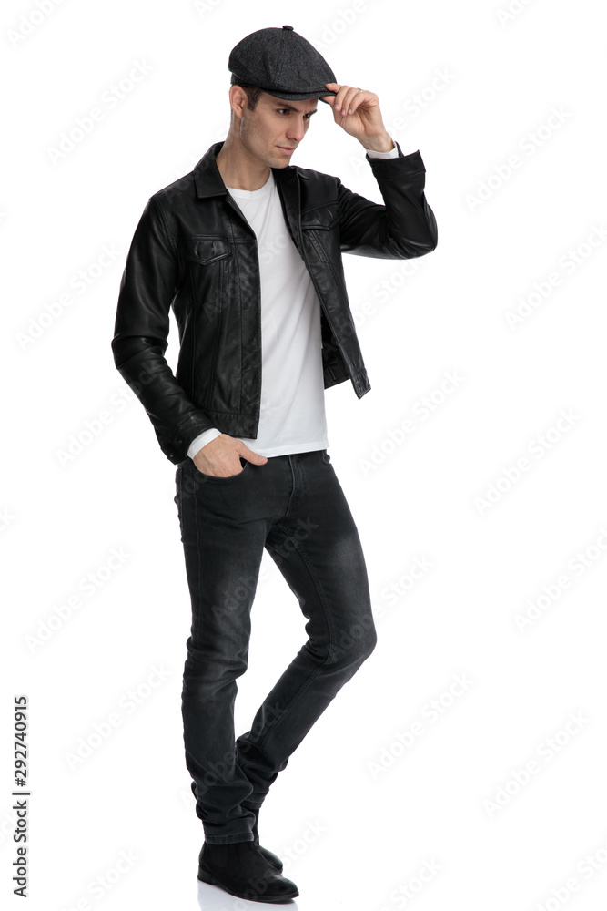 casual man standing and fixing his hat while looking ahead casual man standing and fixing his hat while looking ahead