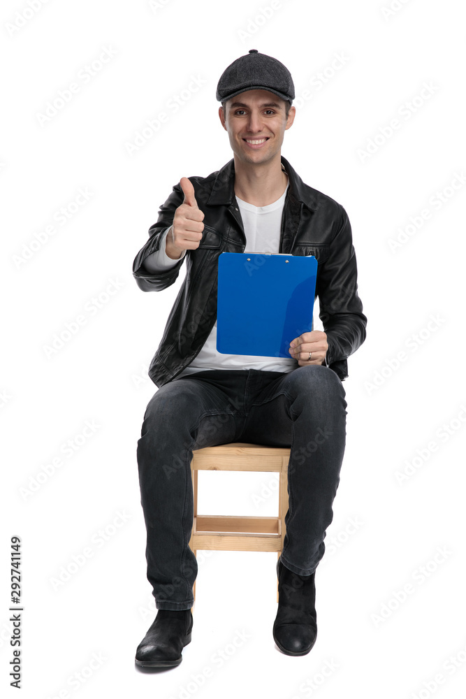 seated casual man holding clipboard and making ok sign seated casual man holding clipboard and making ok sign