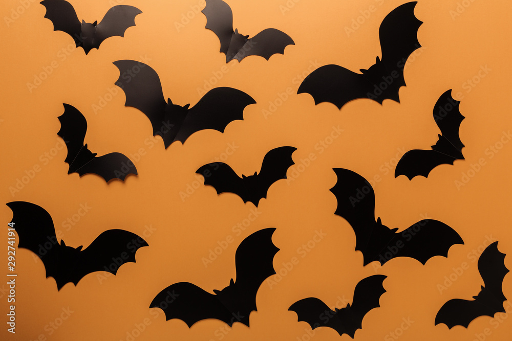 Naklejka premium Halloween black paper bats on orange background. Top view Copy space - Image