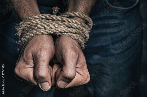 Mens hands tied with a rope, close-up. Concept of imprisonment in modern society photo
