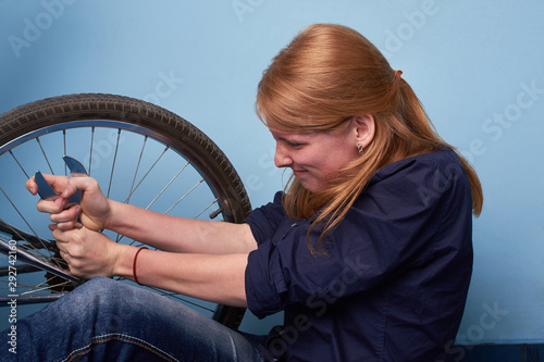 young woman repairing a bike. pretty young girl repairing bicycle in bike shop