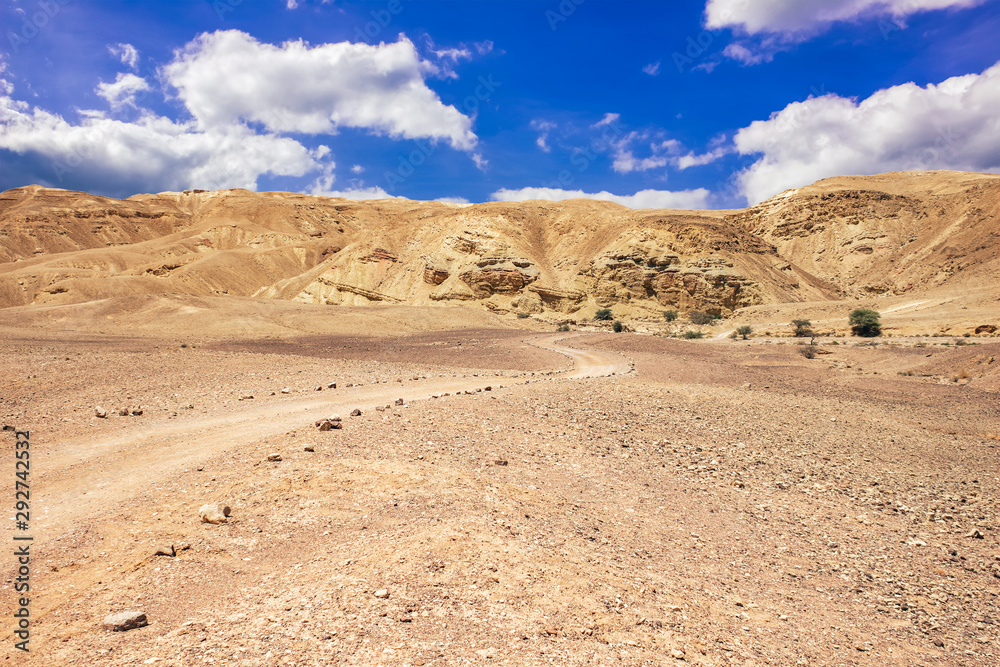 idyllic desert sand stone valley foreground scenery landscape view with horizon background of bare mountain hills and vivid blue sky white clouds idyllic desert sand stone valley foreground scenery landscape view with horizon background of bare mountain hills and vivid blue sky white clouds