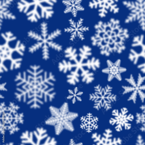Christmas seamless pattern of white defocused snowflakes on blue background