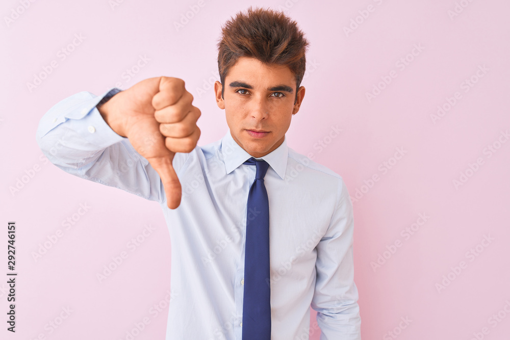 Young handsome businessman wearing shirt and tie standing over isolated pink background looking unhappy and angry showing rejection and negative with thumbs down gesture. Bad expression. Young handsome businessman wearing shirt and tie standing over isolated pink background looking unhappy and angry showing rejection and negative with thumbs down gesture. Bad expression.
