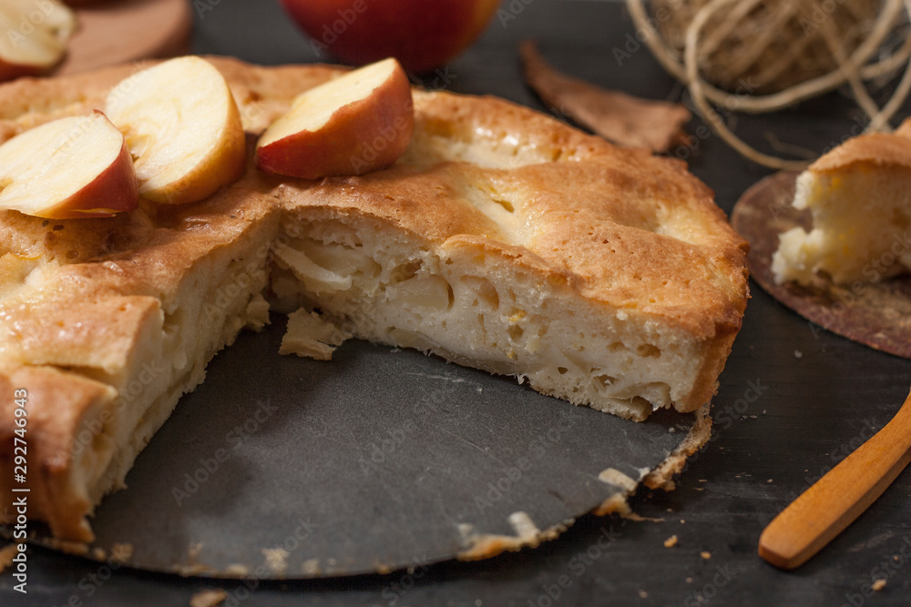 Charlotte apple pie on a black wooden table with slices of red apples