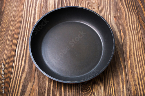 Empty round pan for cooking on wooden background, selective focus, top view
