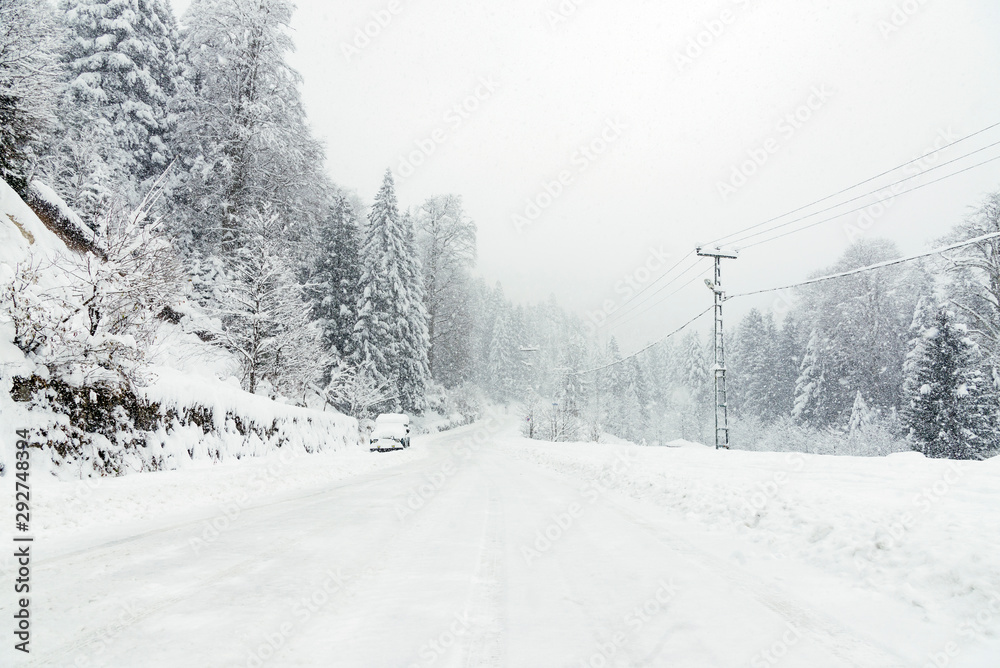 Fototapeta premium Snowy road in winter with an SUV parked.