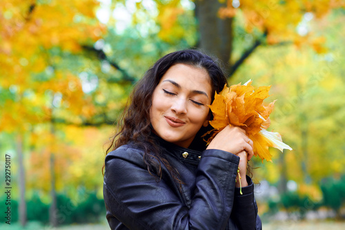 woman posing with autumn leaves in city park  outdoor portrait