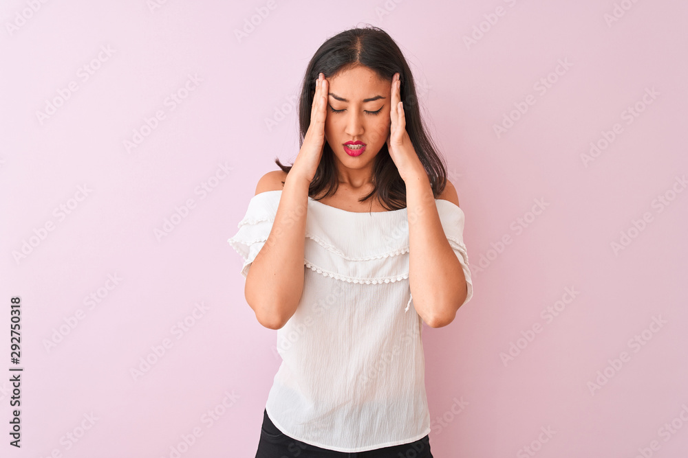 Beautiful chinese woman wearing white t-shirt standing over isolated pink background with hand on head for pain in head because stress. Suffering migraine. Beautiful chinese woman wearing white t-shirt standing over isolated pink background with hand on head for pain in head because stress. Suffering migraine.