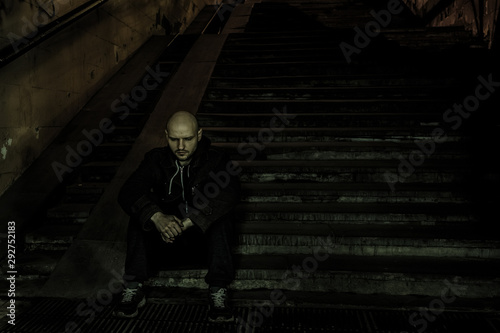 Depressive sad man sitting in on stairs of dark street subway. Despair concept