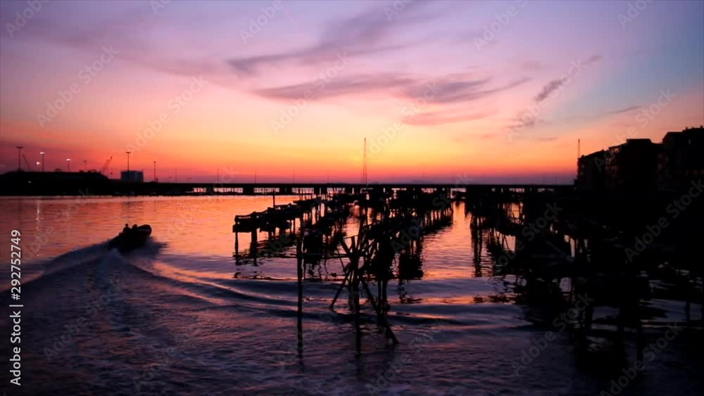 sunset over the Chioggia lagoon (Italy) with a passing boat, and mussel farming sunset over the Chioggia lagoon (Italy) with a passing boat, and mussel farming