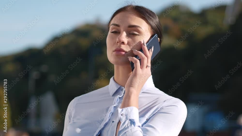 Young independent business woman talking on a cell phone while standing on the square. Close up 4k Young independent business woman talking on a cell phone while standing on the square. Close up 4k