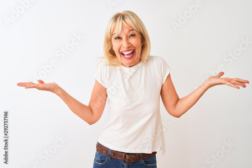 Middle age woman wearing casual t-shirt standing over isolated white background celebrating crazy and amazed for success with arms raised and open eyes screaming excited. Winner concept