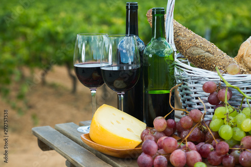 Red wine with cheese, bread in basket and grapes
