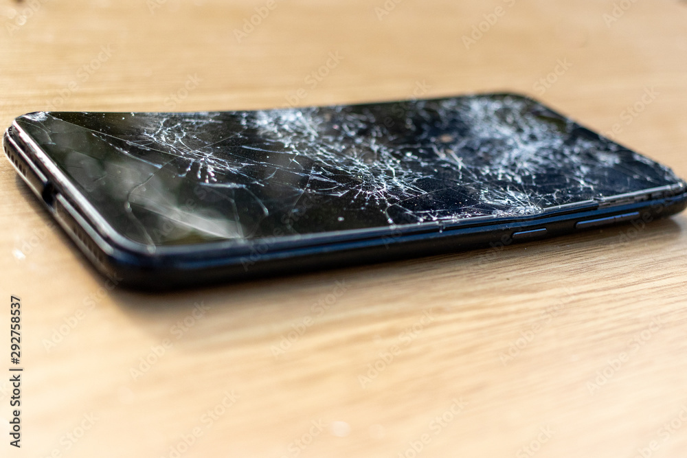 Broken screen cell phone on light background. Old broken black smartphone  on the table. Close up photos showing process of mobile phone repair.  Smartphone and wooden hummer. Stock-Foto | Adobe Stock