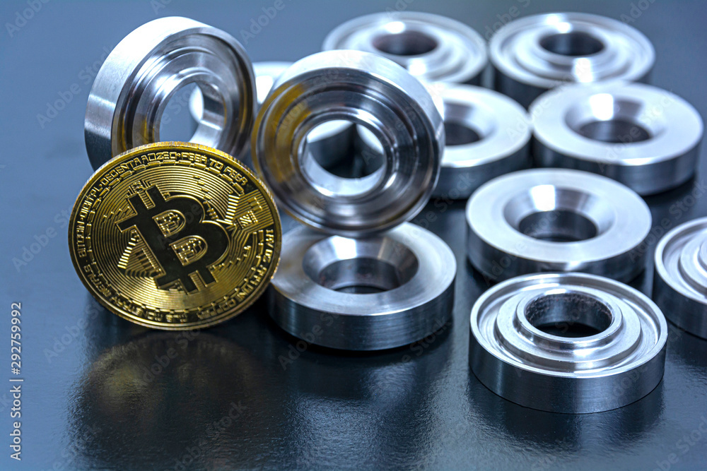 details machined on a lathe and bitcoin on a black background. The concept of real and virtual income, earnings on the Internet and in real conditions. details machined on a lathe and bitcoin on a black background. The concept of real and virtual income, earnings on the Internet and in real conditions.