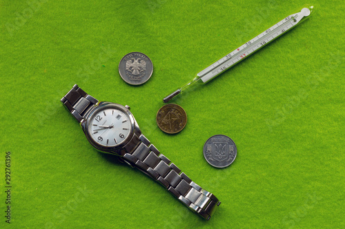 Time heals. Clock, coins of Ukraine, Russia, Belarus, medical thermometer.