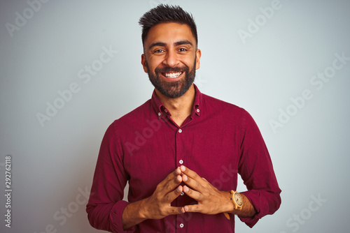 Foto Young indian man wearing red elegant shirt standing over isolated grey background Hands together and fingers crossed smiling relaxed and cheerful
