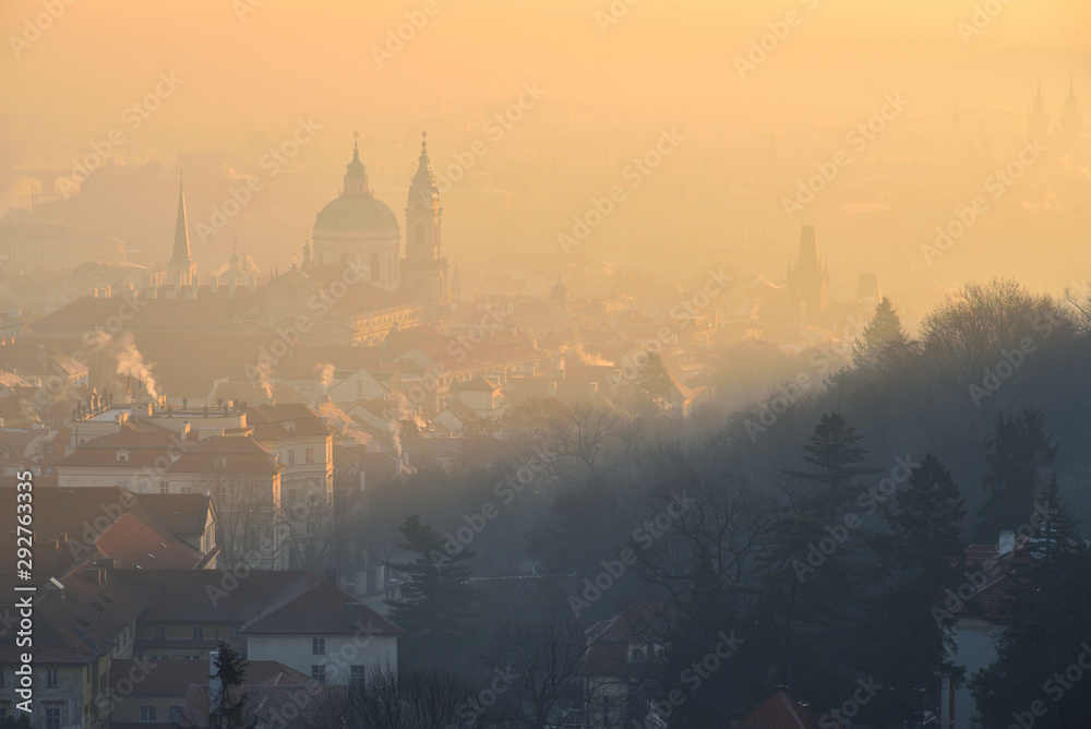 Naklejka premium Winter morning in the Mala Strana district - historical part of Prague, Czech Republic. St. Nicholas Church. Sunrise. Fog. View from the Strahov Monastery.