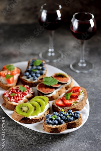 Healthy vegetarian sandwiches made from rye bread with soft cheese  organic berries and fruits - strawberries  blueberries  kiwi  figs  pomegranate seeds and mint.