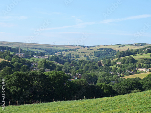 a scenic view of the calder valley with the village of luddenden between trees and surrounding hillside fields