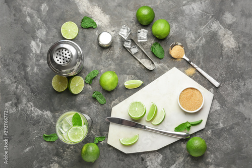 Glass of fresh mojito with ingredients on grey background