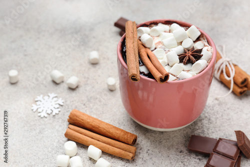 Cup of hot chocolate with marshmallows and cinnamon on light background