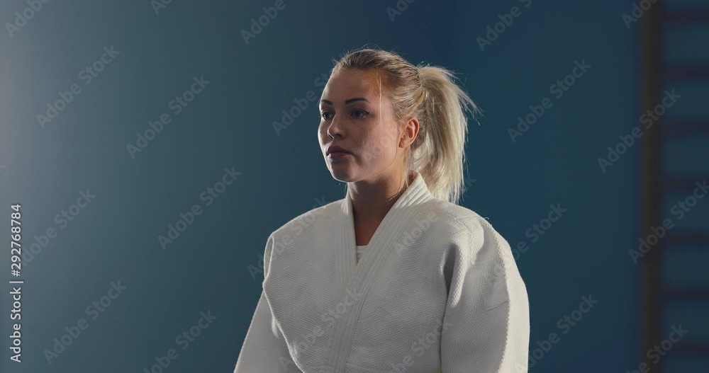 Young girl in a white kimono tunes in for a fight. Serious look of a fighter. Portrait view.