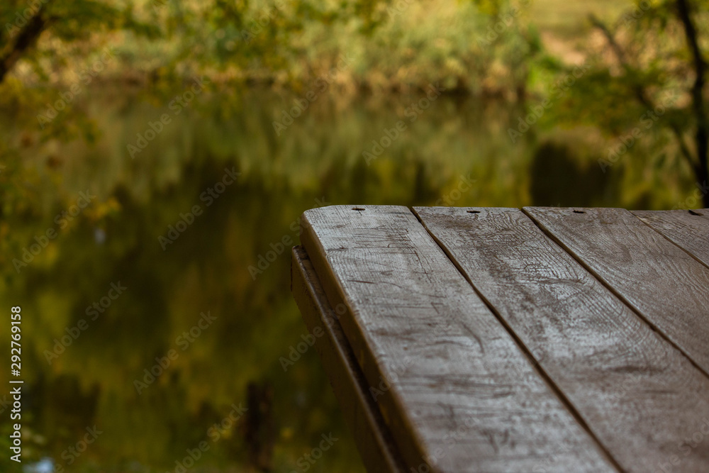 Fototapeta premium Part of wood table near the river, green background