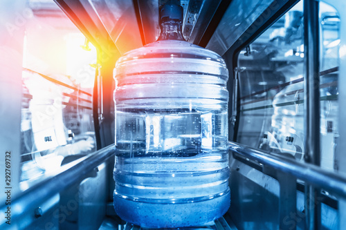 Photos Plastic bottle or gallon of purified drinking water inside automated conveyor production line