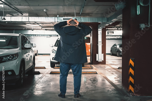 Stolen car concept. Surprised man discovered loss of car in underground garage parking lot, holding his head by hands