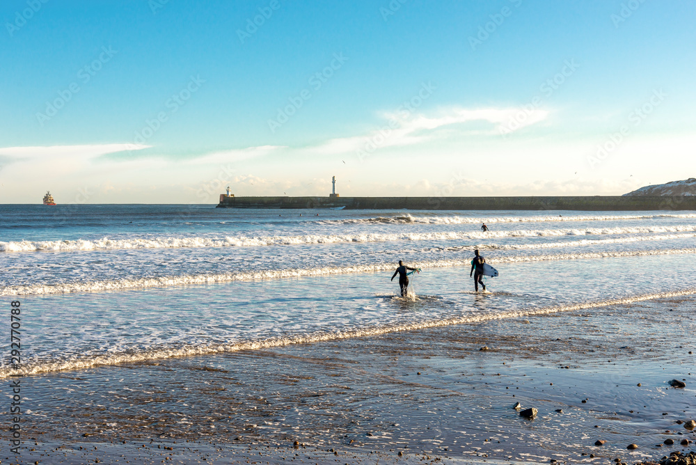 A couple of surfers enter water on Aberdeen beach near South breakwater, Scotland