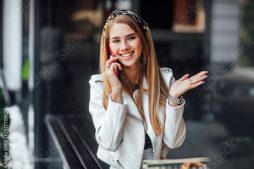 Attractive woman in luxiry outfit speaking by her phone  while walking in the summer city.